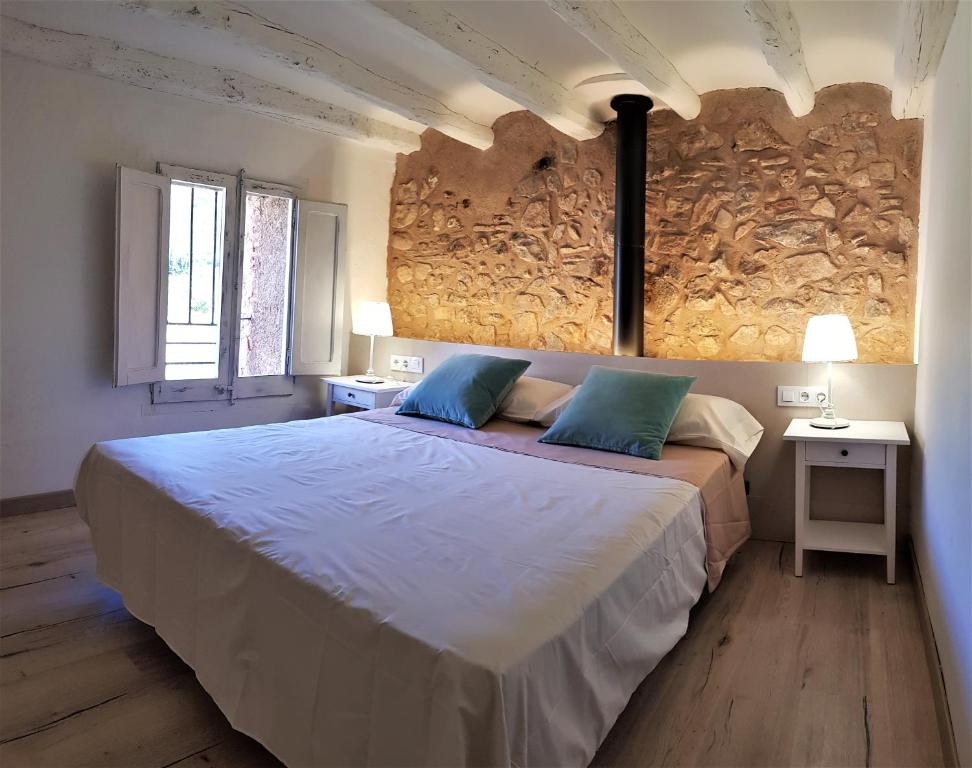 1 dormitorio con 1 cama grande y pared de piedra en Cal Moreno en Pratdip