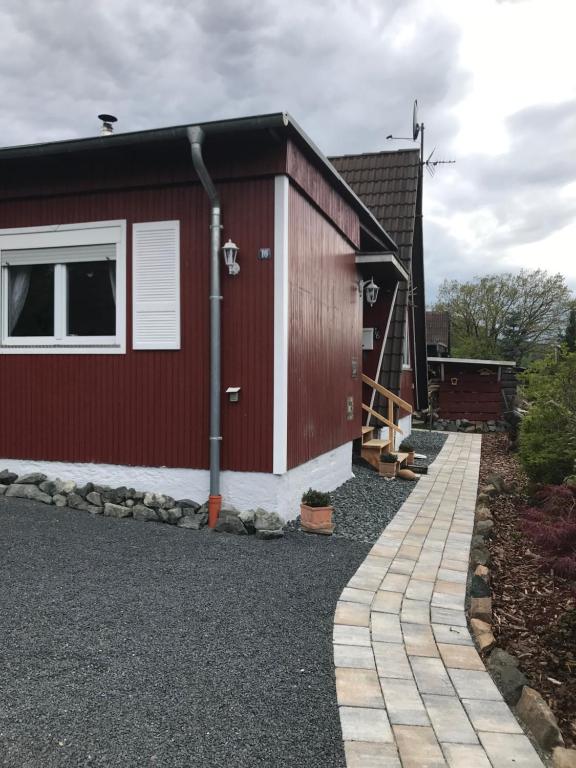 a red building with a window and a sidewalk at Ferienhaus Schädertalblick in Wolfshagen