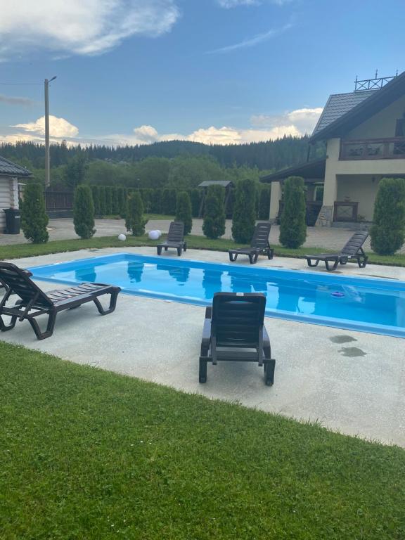 a swimming pool with benches around it with mountains in the background at VIP House cottages in Mykulychyn