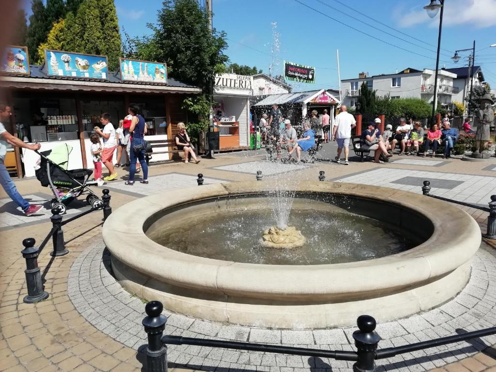 a fountain in the middle of a street with a crowd of people at Pokoje przy fontannie in Karwia