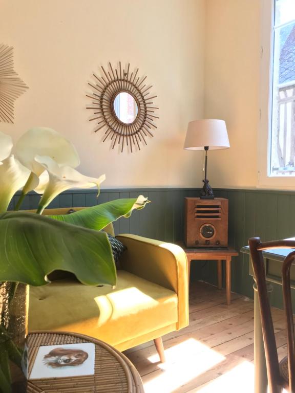 sala de estar con sofá amarillo y espejo en AU NAIN ROUGE gite vintage de charme, en Cormeilles