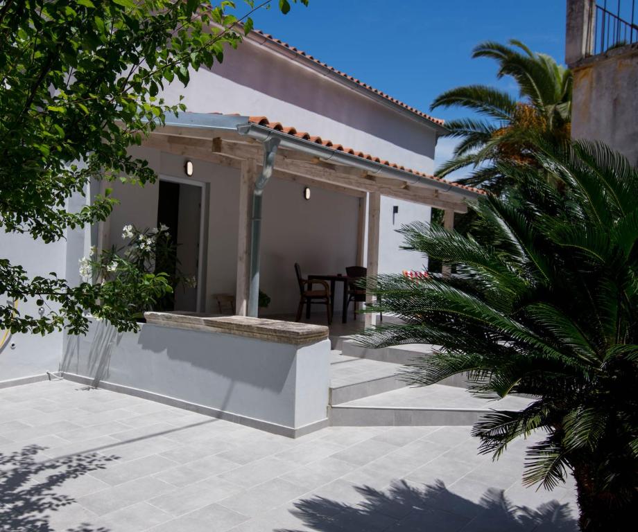 Dieses weiße Haus verfügt über eine Terrasse mit einem Tisch. in der Unterkunft Alice A1 in Veli Lošinj