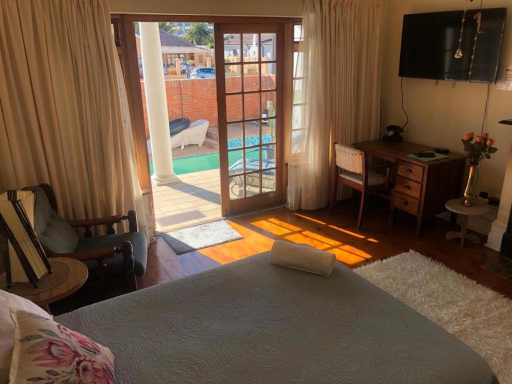 a bedroom with a bed and a desk and a television at Sunny private room on the porch in Port Elizabeth