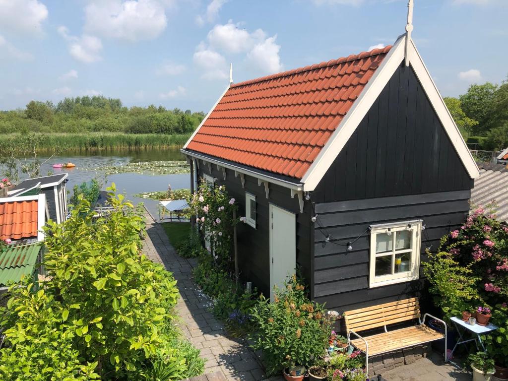 una casa negra con techo rojo junto a un lago en Het Pulletje, en Westzaan