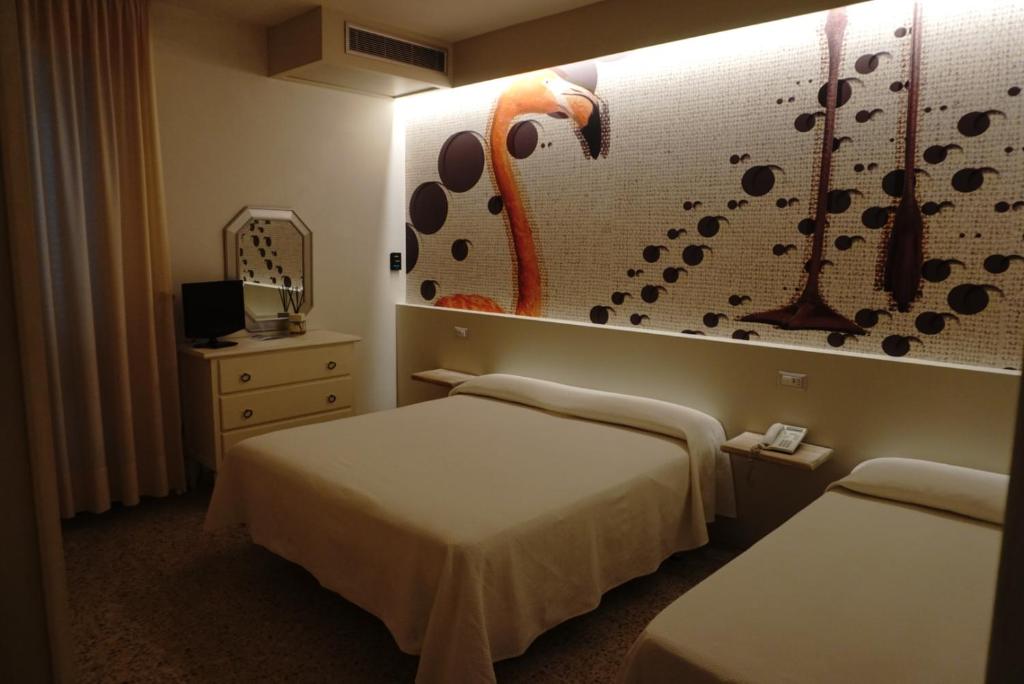 a hotel room with two beds and a wall with a mural at Hotel Atlantico in Castiglioncello
