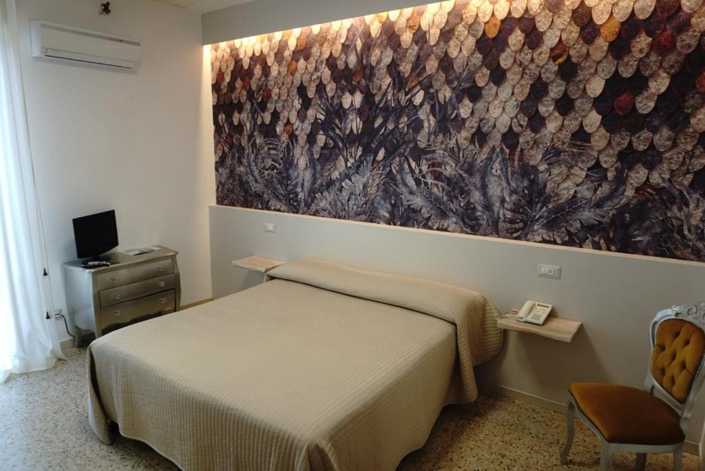 a bedroom with a bed and a painting on the wall at Hotel Atlantico in Castiglioncello
