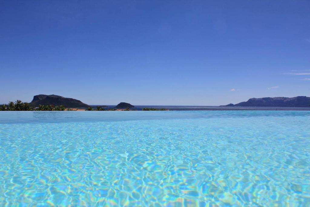 une grande étendue d'eau bleue avec des montagnes en arrière-plan dans l'établissement VILLA ALBA NUOVA with infinity pool & amazing sea view, à Golfo Aranci