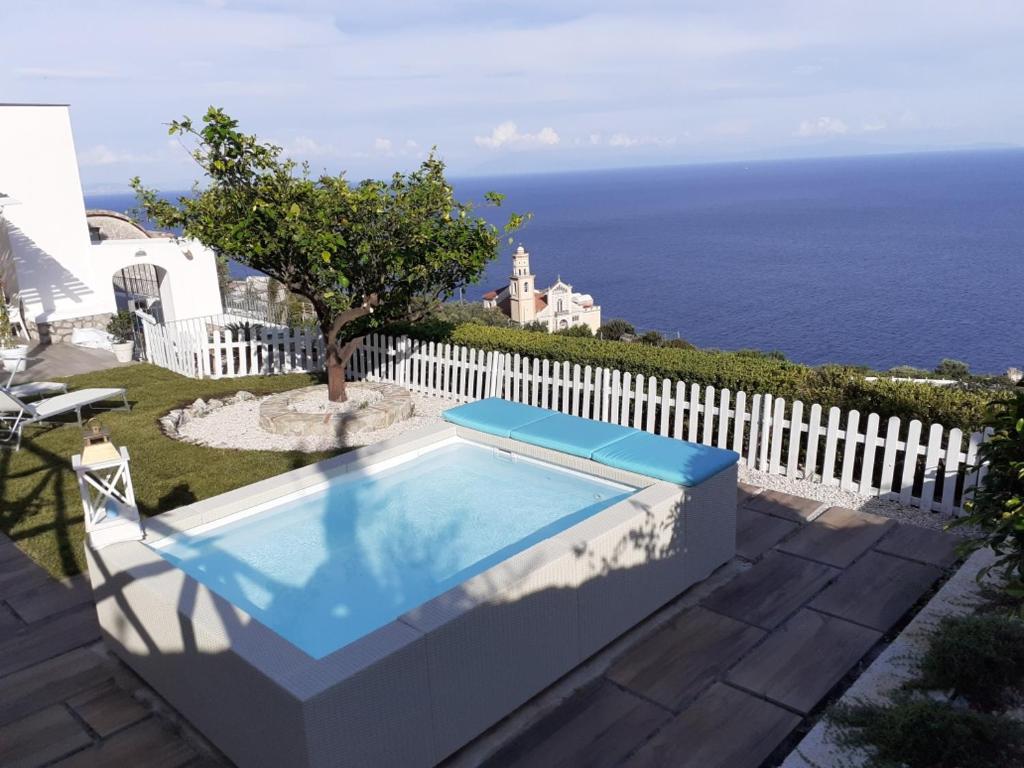 una piscina di fronte a una recinzione bianca e all'oceano di Villa Marilisa a Conca dei Marini