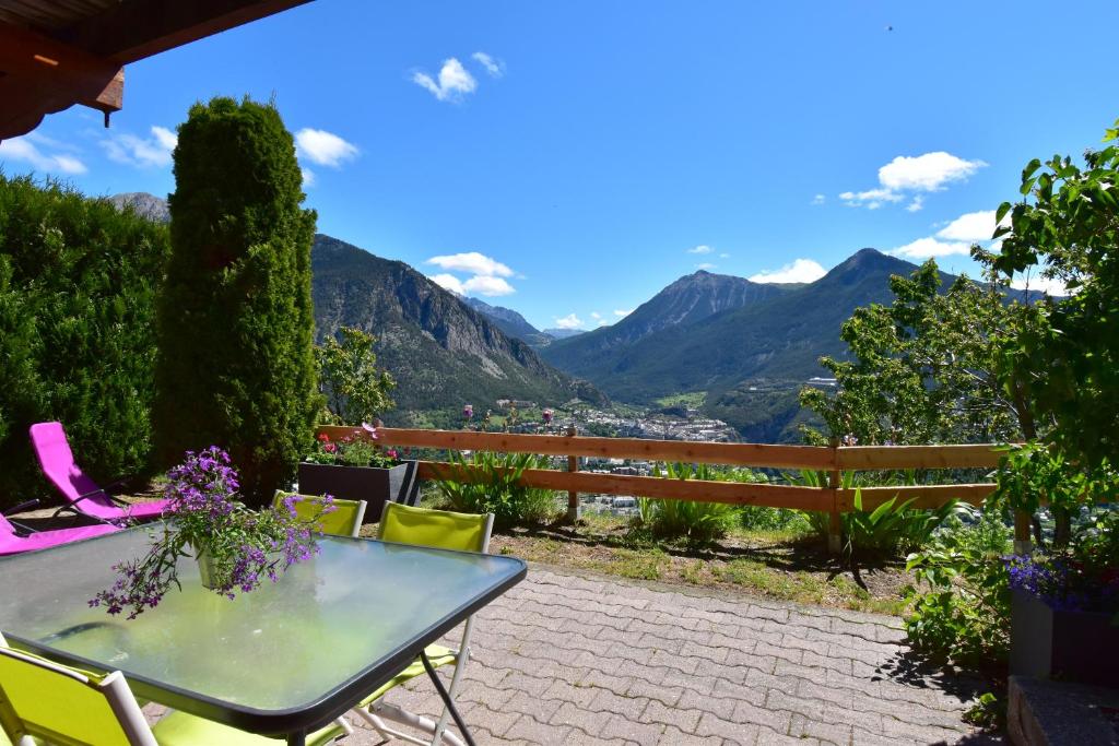 a table and chairs on a patio with mountains in the background at CHALET SERRE CHEVALIER AVEC VUE EXCEPTIONNELLE in Puy-Saint-Pierre
