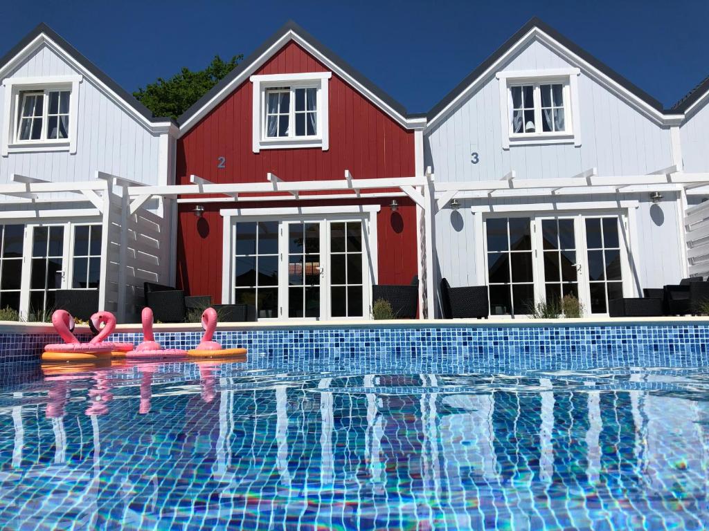 a swimming pool with pink flamingos in front of a house at Mamma Mia Resort in Łukęcin