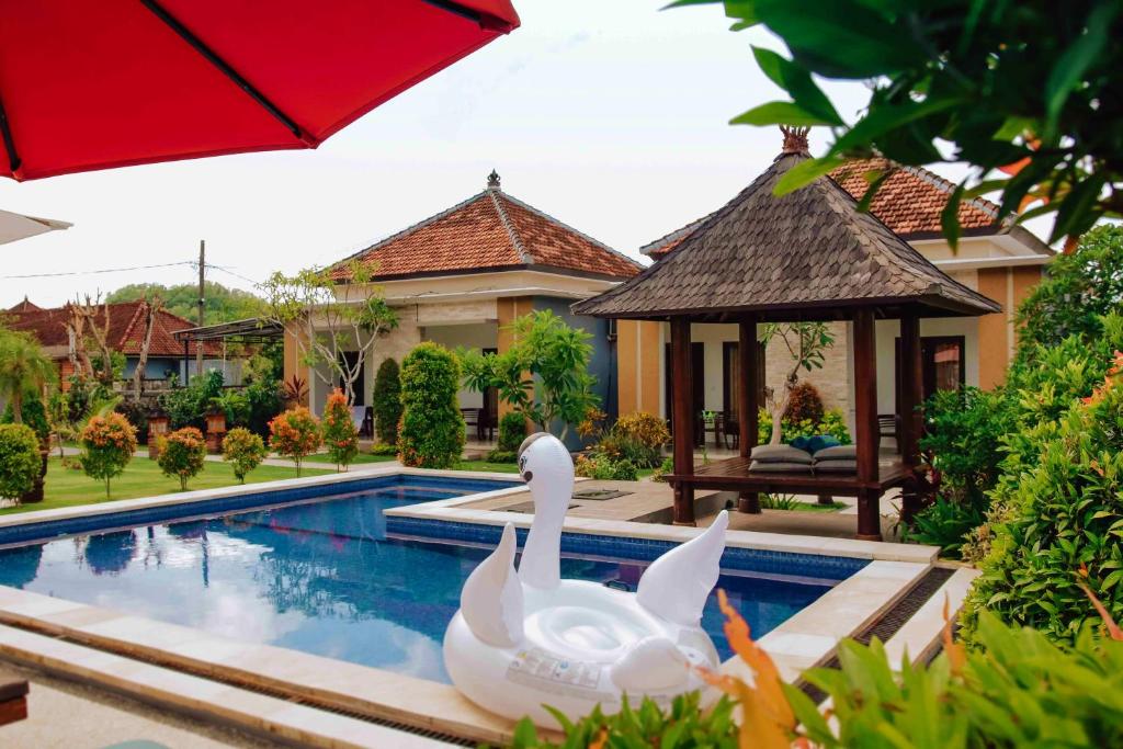 two swans in a swimming pool in front of a house at Uluwatu Jungle Villa in Uluwatu