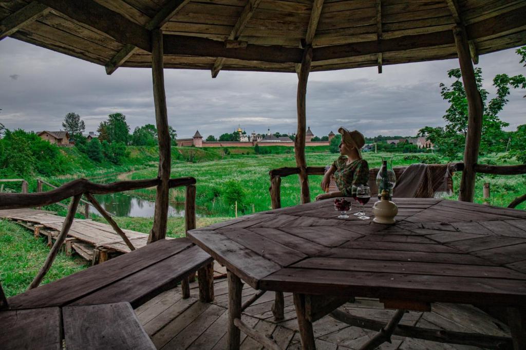 a woman sitting at a wooden table in a pavilion at Suzdal Spasskaya Gorka in Suzdal