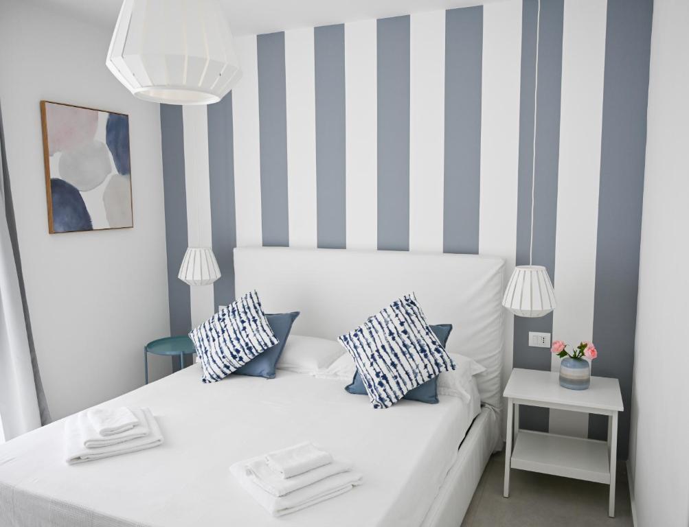 a bedroom with a white bed with blue and white stripes at L'Ancora B&B in Milazzo