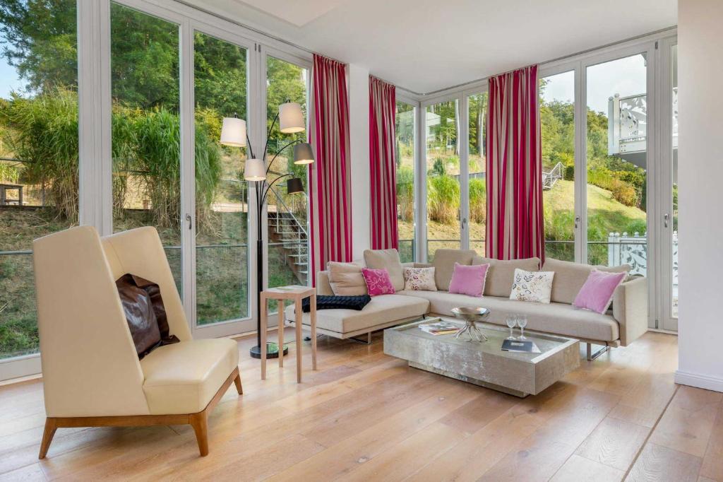 ein Wohnzimmer mit einem Sofa, Stühlen und Fenstern in der Unterkunft Villa Theres Dolphin in Ostseebad Sellin