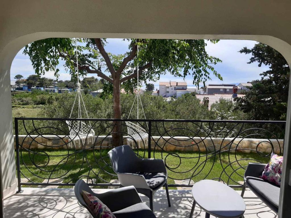 un balcón con sillas, mesas y un árbol en Apartment Mia, en Rab