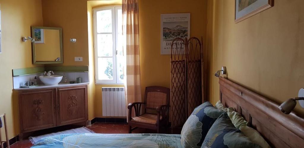 een slaapkamer met een bed, een wastafel en een raam bij Les Tournesols in Mallemort