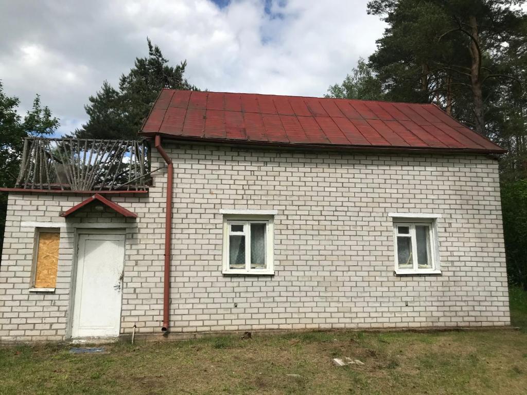 een klein wit bakstenen huis met een rood dak bij Pine trees in Evarti