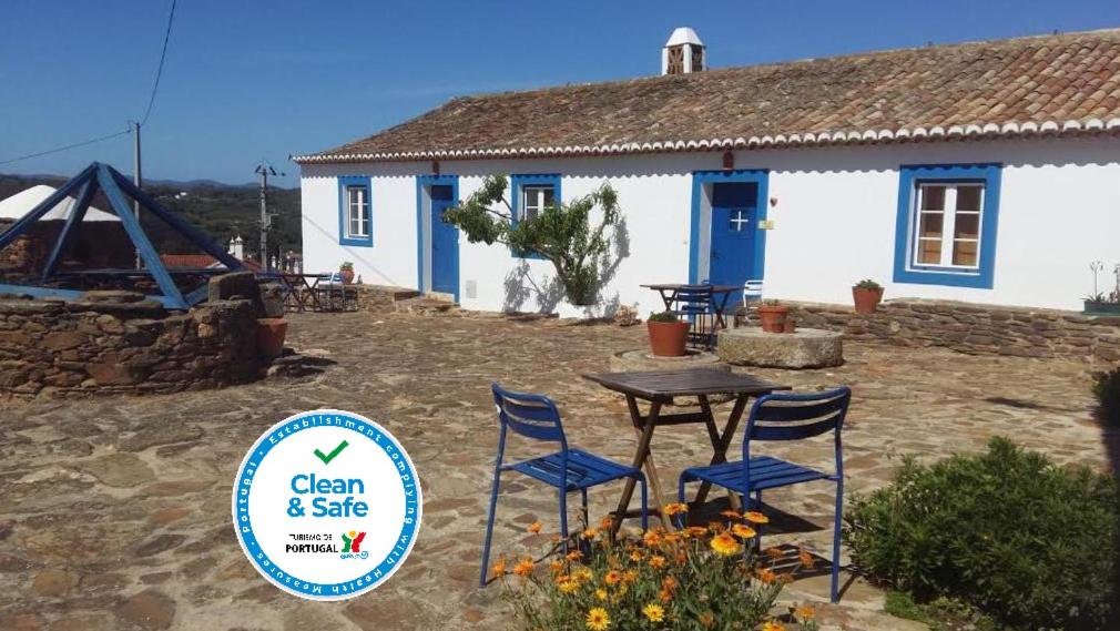 a table and chairs in front of a house at Herdade Do Azinhal in Santa Clara-a-Velha