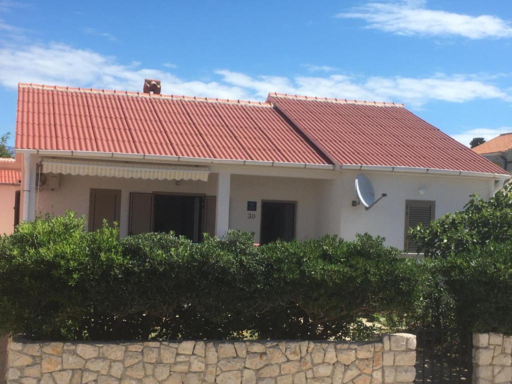 ein Haus mit einem roten Dach und einer Steinmauer in der Unterkunft Luce in Povljana