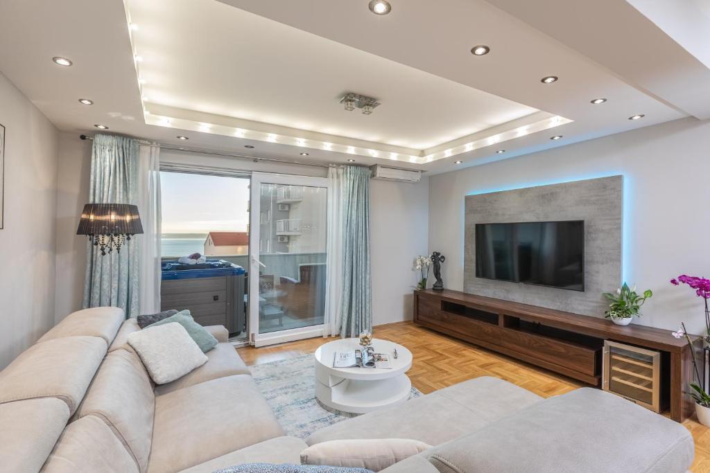 a living room with a large couch and a tv at Luxury apartman SKY with sea view and whirlpool in Makarska