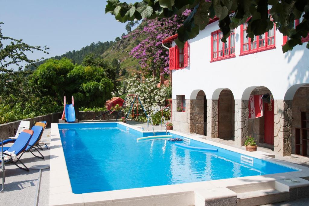 a swimming pool in front of a house at Casa Do Palheiro in Covelas