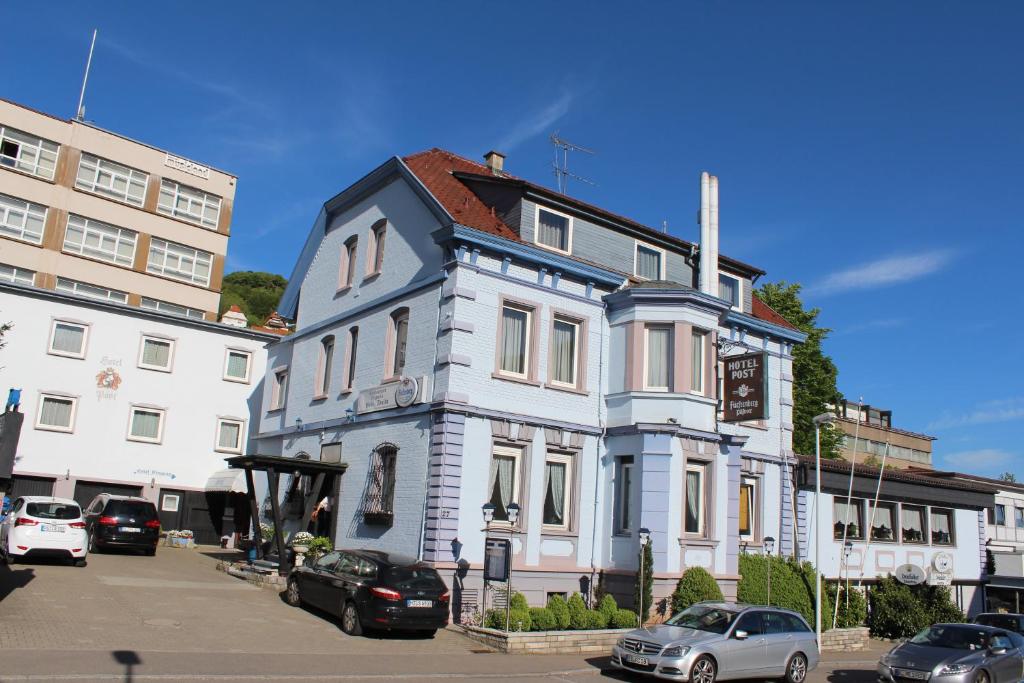 a blue and white house with cars parked in a parking lot at Hotel Restaurant Post Italia in Albstadt