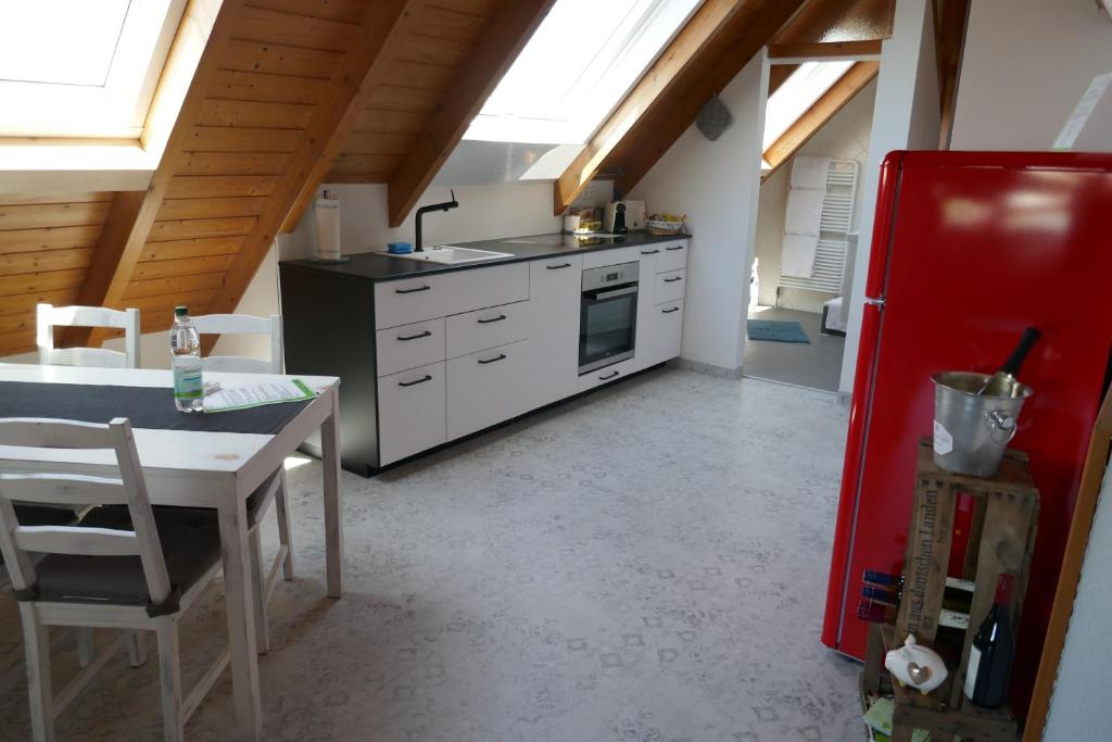 a kitchen with a table and a red refrigerator at Moderne 2 Zi - FeWo Weinbergliebe am Tuniberg zwischen Freiburg und Frankreich in Merdingen