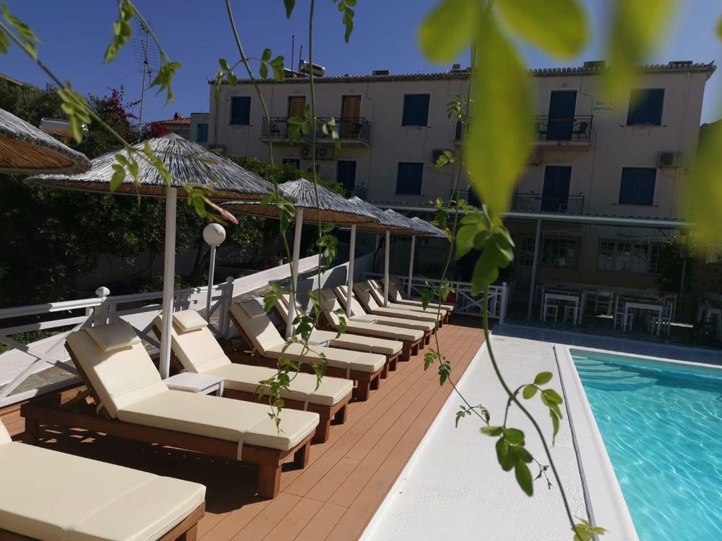 a row of lounge chairs next to a swimming pool at Bay's in Spetses