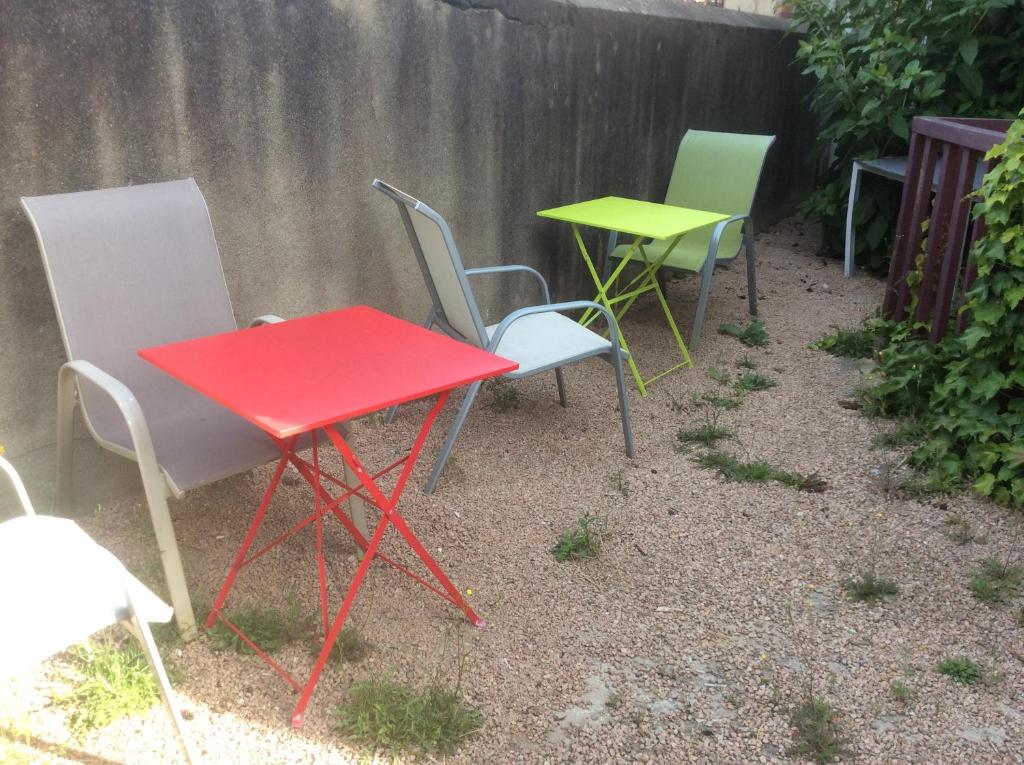 3 sillas y una mesa roja y sillas en un patio en L&#39;appart de Clea, en Montluçon