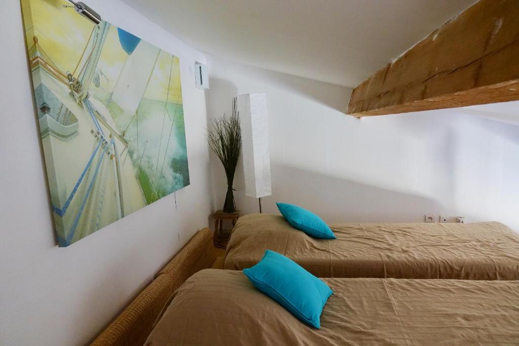 2 Betten in einem kleinen Zimmer mit blauen Kissen in der Unterkunft Beach, Wine, Dining, Sports, Summer, Winter in Sérignan