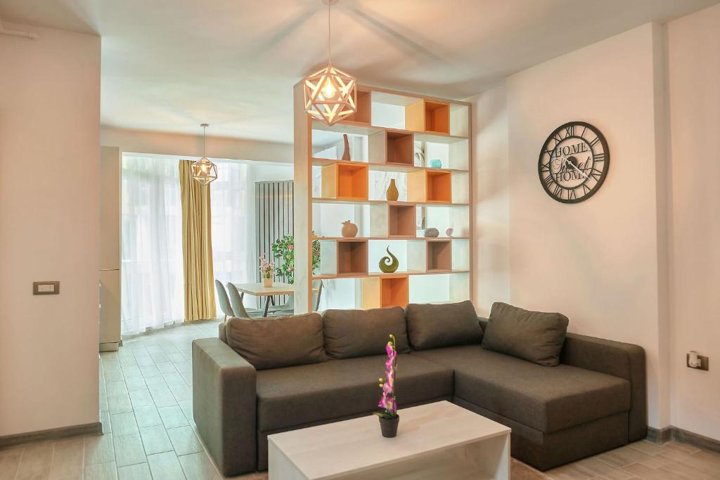 a living room with a couch and a clock on the wall at Fanta Sea Apartament Spa n Pool Beach resort in Mamaia Sat/Năvodari