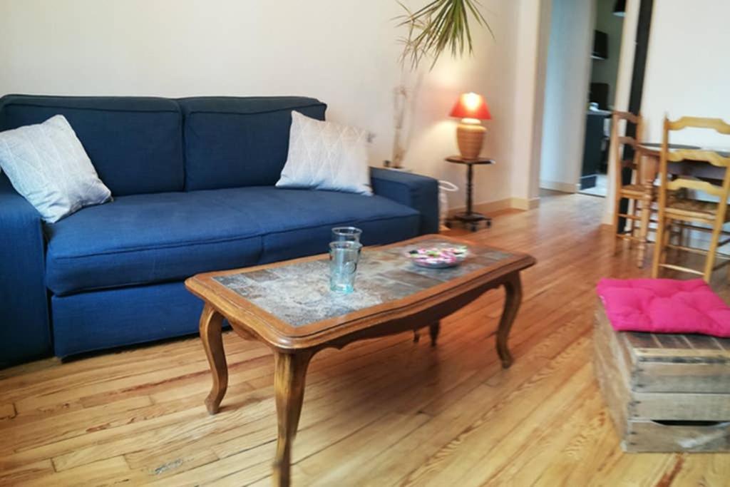 a living room with a blue couch and a coffee table at Le charme de l ancien entre mer et ville in Le Havre