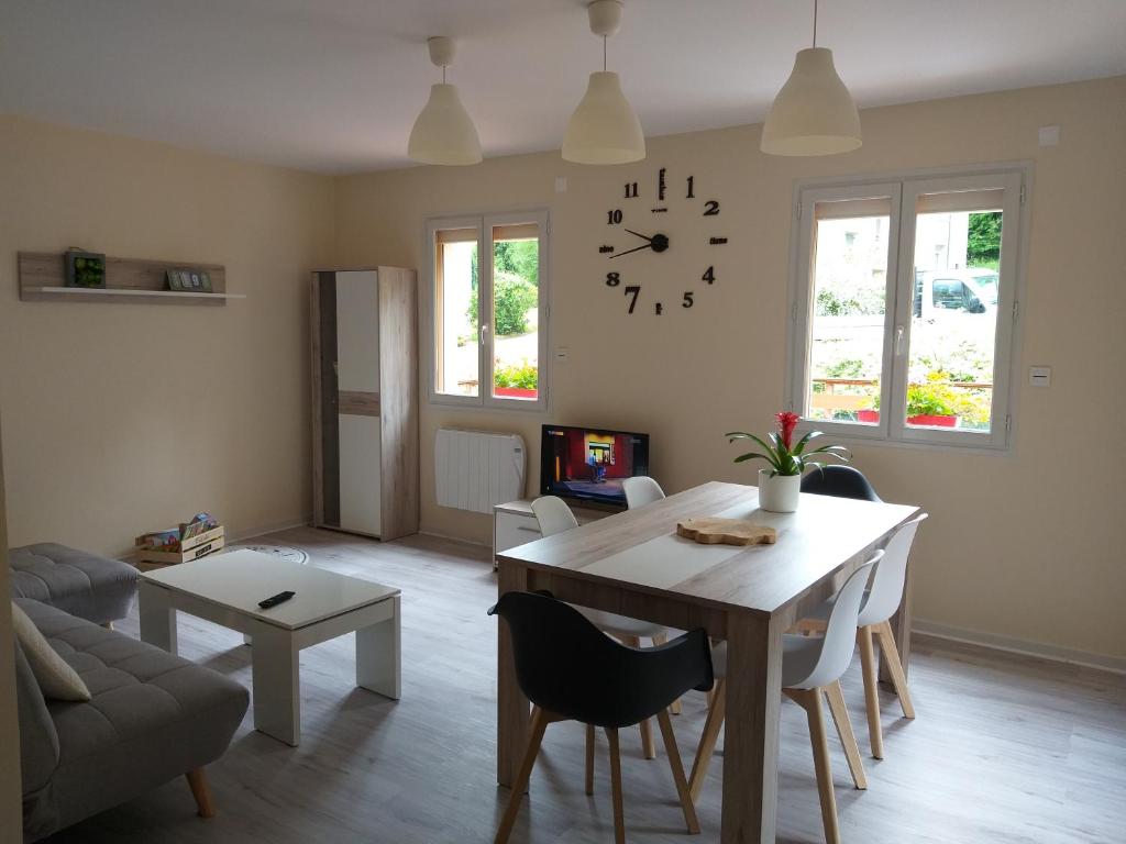 een woonkamer met een tafel en een klok aan de muur bij Location A.M.I in Bellegarde-sur-Valserine