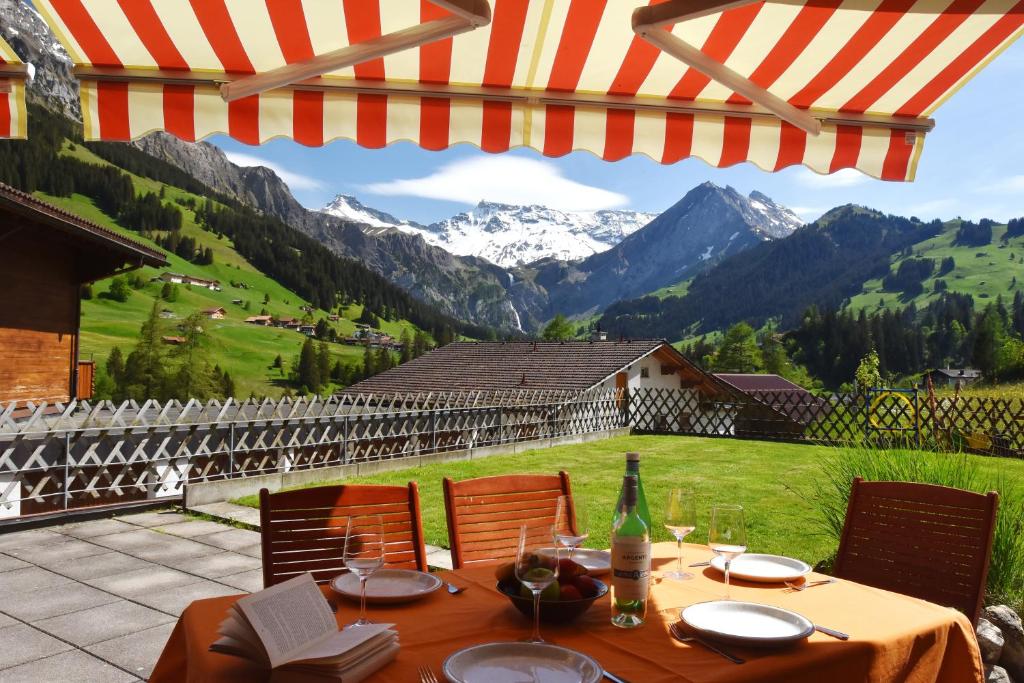 a table with chairs and an umbrella with a view of mountains at Appartment Andrea in Adelboden