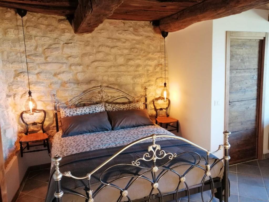 - une chambre avec un lit en métal dans un mur en pierre dans l'établissement Casa San Biagio, à Pergola