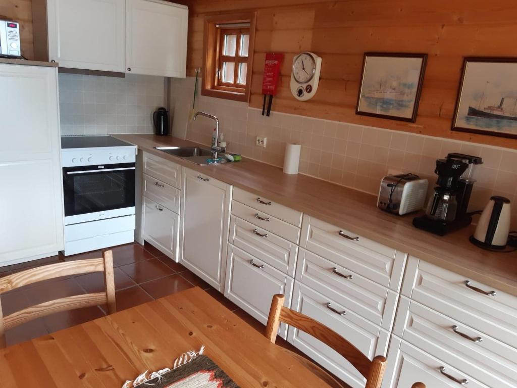 a kitchen with white cabinets and a wooden floor at Hus med sjøutsikt in Frafjord