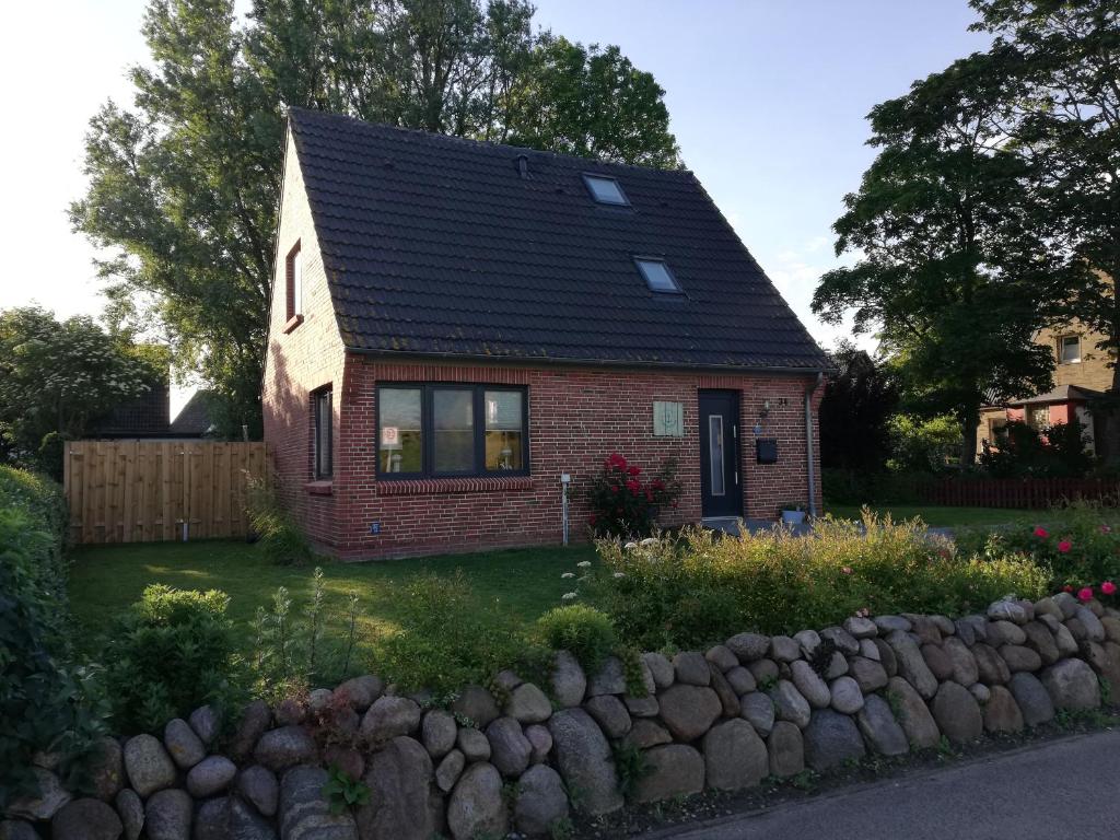 een klein rood bakstenen huis met een zwart dak bij Nordlichthuus in Tönning