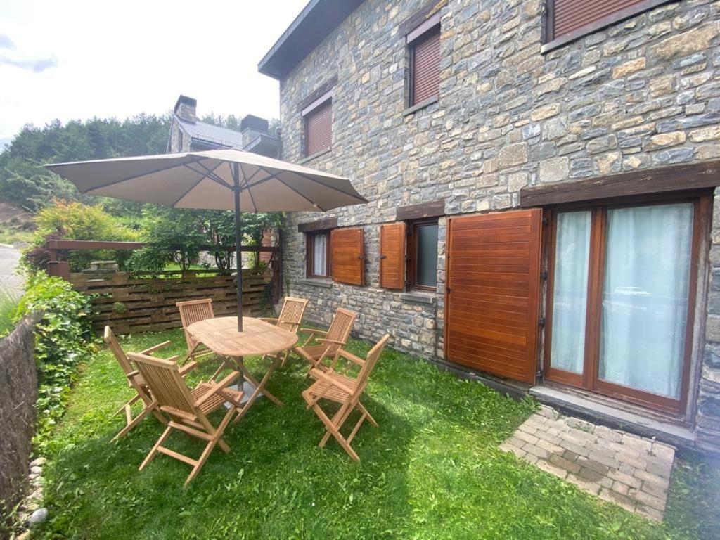 a table and chairs with an umbrella in front of a building at Fantástico Apartamento con jardín en Castiello de Jaca in Castiello de Jaca