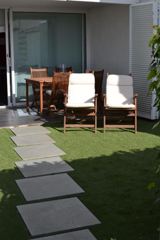 un patio con 2 sillas y una mesa en el césped en Bonito apartamento con jardín, en Platja d'Aro