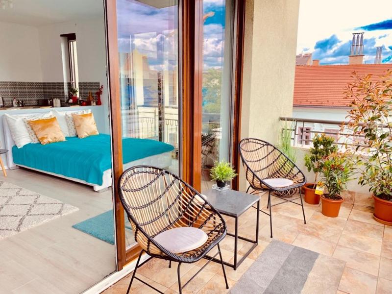 een patio met 2 stoelen en een bed op een balkon bij Sunny Deluxe Apt. & Terrace in Boedapest