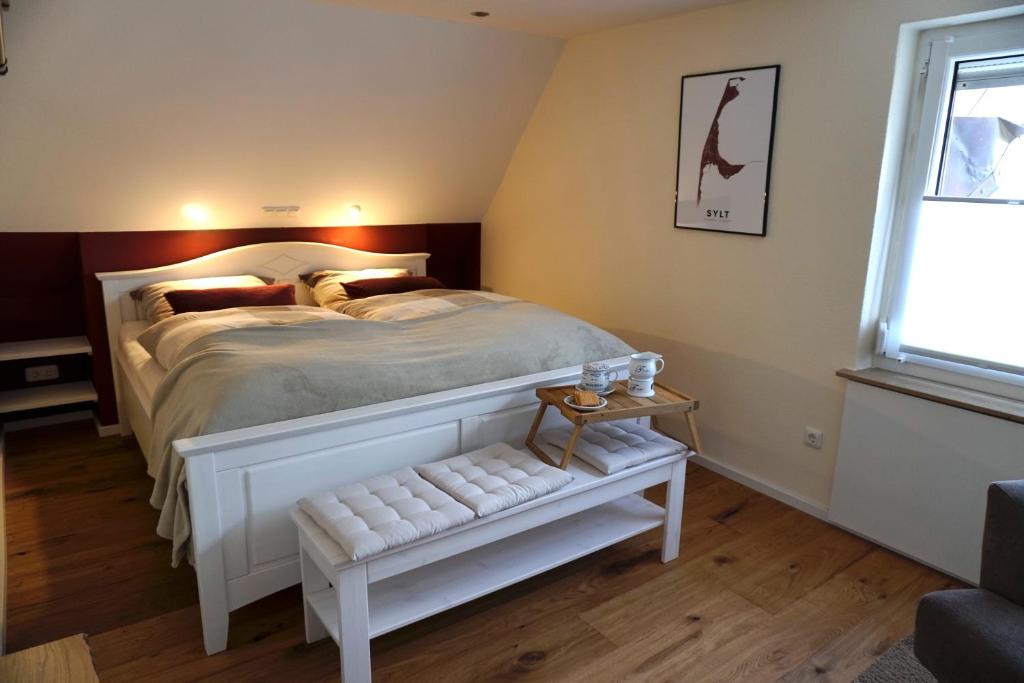 a bedroom with a white bed with a bench in it at Tier- & kinderfreundliches Ferienhaus - KEINE MONTEURE in Priesendorf