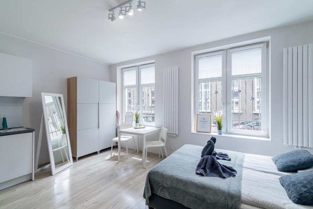 a white bedroom with a bed and a desk at Apartment New & Nice in Gdańsk