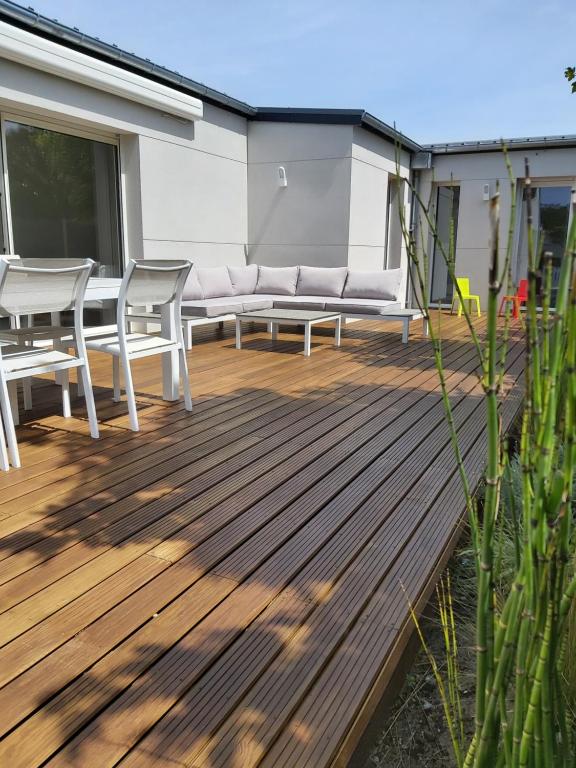 eine Holzterrasse mit einer Bank und einem Tisch in der Unterkunft Beachdisa in Saint-Pair-sur-Mer