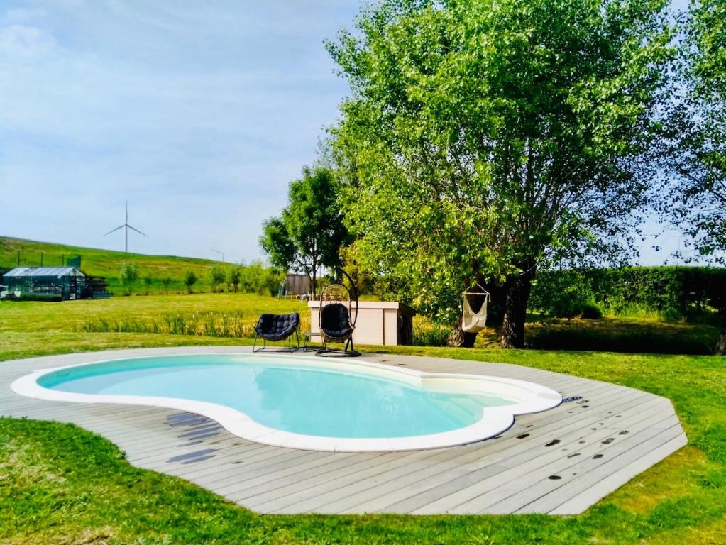 een zwembad met een terras en een stoel in een tuin bij Demeure de charme haut de gamme - Piscine chauffée in Lissewege