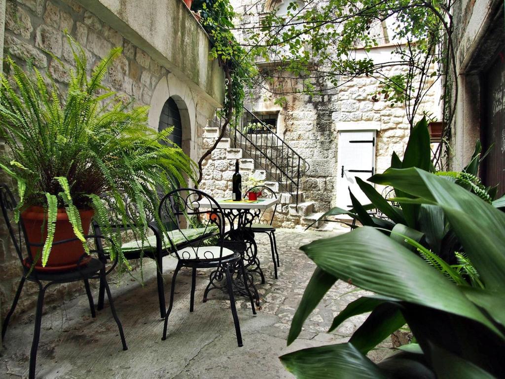 eine Außenterrasse mit Tischen, Stühlen und Pflanzen in der Unterkunft Rooms & Studio Stipcic in Trogir
