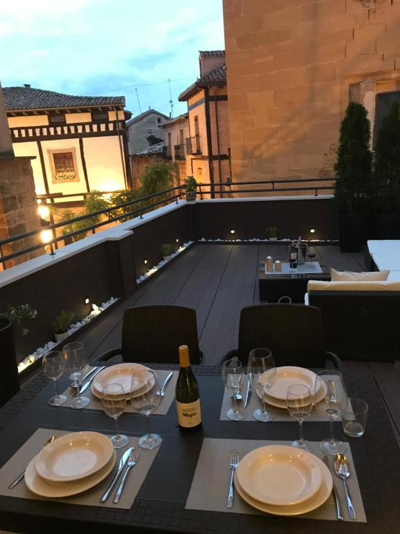 una mesa con platos y copas de vino en el balcón en Apartamentos La Herradura Terraza, en Haro