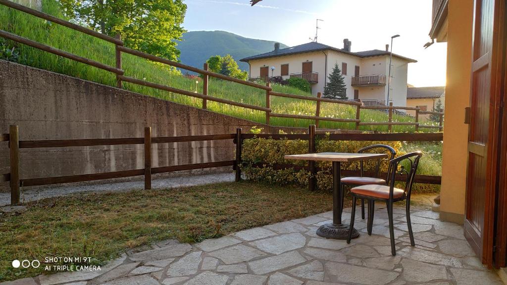 un patio con una mesa y 2 sillas y una valla en Locazione Turistica Sestola con giardino, en Sestola