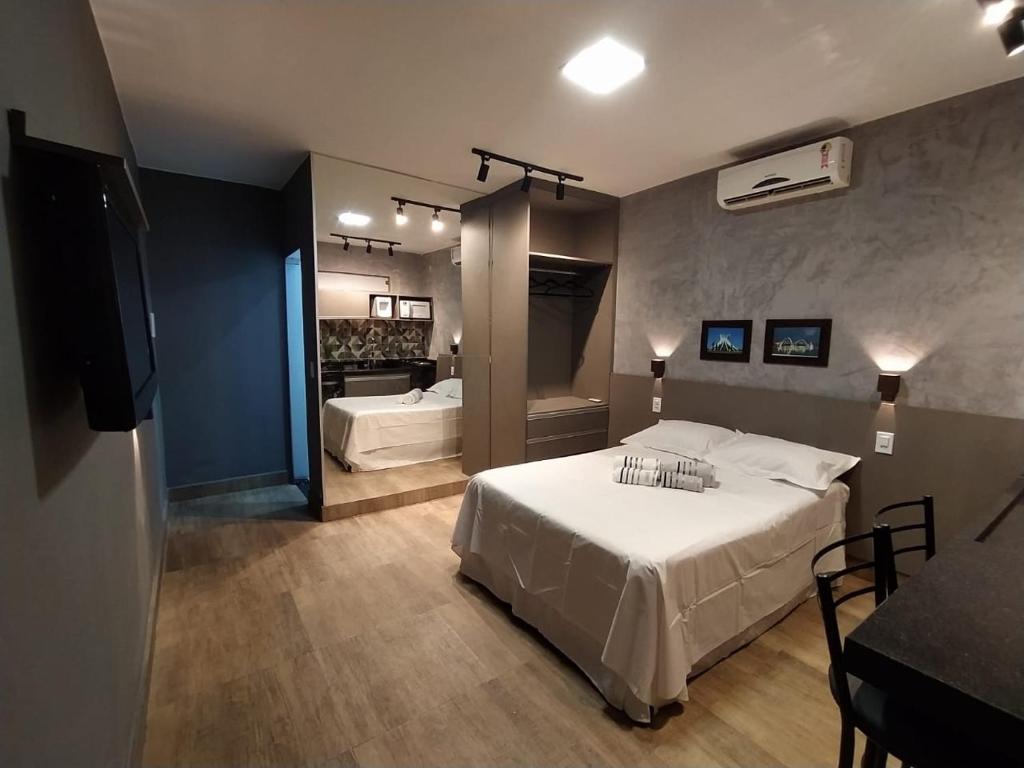 a bedroom with a white bed and a bathroom at KIT/LOFT - MUITO PRÓXIMA AO AEROPORTO DE BRASÍLIA in Brasilia
