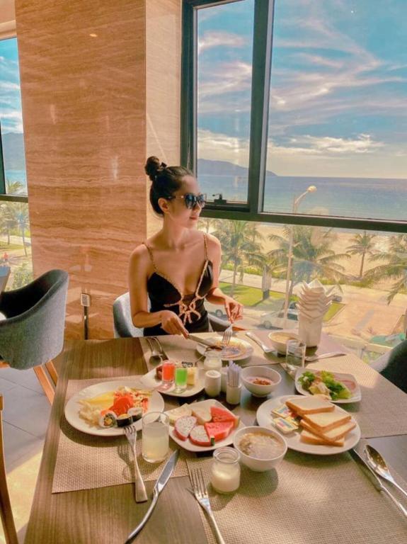 A breakfast table sits beside large windows overlooking the beach and sea.