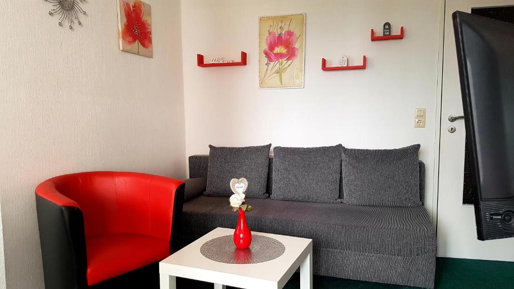 - un salon avec un canapé et un fauteuil rouge dans l'établissement Ferienwohnung Sweety Haus Sachsensteinblick, à Bad Sachsa